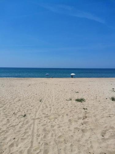 a sandy beach with an umbrella and the ocean at Appartamento Salvia in centro in Ascea