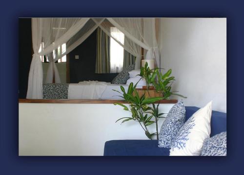 a bedroom with a bed and a blue couch with pillows at L'Hirondelle Self Catering Guest House in Anse Possession