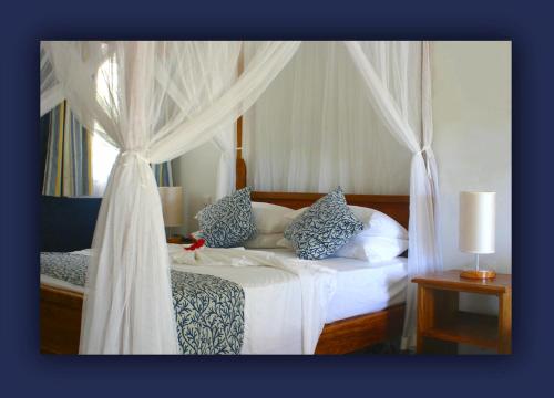 a bedroom with a white bed with a canopy at L'Hirondelle Self Catering Guest House in Anse Possession
