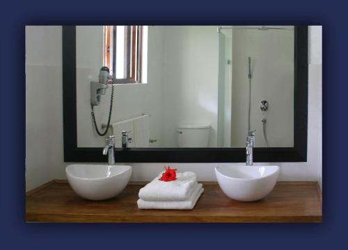 a bathroom with two white sinks and a large mirror at L'Hirondelle Self Catering Guest House in Anse Possession