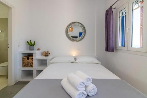 a white bedroom with a bed with towels on it at Sail Inn in Agios Romanos