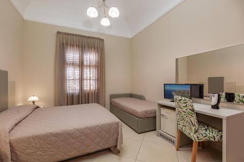 a bedroom with a bed and a desk with a computer at Ghibli Hotel in San Vito lo Capo