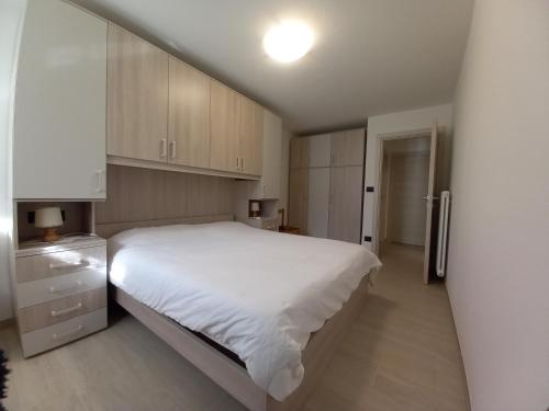 1 dormitorio con 1 cama blanca grande y armarios de madera en Casa con vista a Moena, en Moena