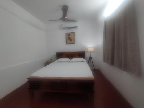 a small room with a bed in a white room at SuKun Heritage in Kannur
