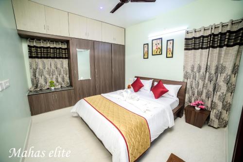 a bedroom with a large bed with red pillows at MAHAS Elite by MAHAS Homestays - 2BHK Flats - Fully Airconditioned in Tirupati