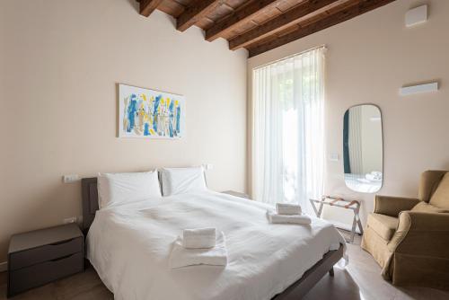 a bedroom with a large white bed and a couch at REGO APARTMENTS - Boutique Aparthotel with some off-site apartments in a Charming Historic District close to Upper Town in Bergamo