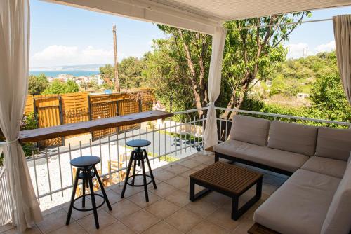 a living room with a couch and stool on a balcony at Grand Seaview Retreat - walk to the beach in Neoi Epivates