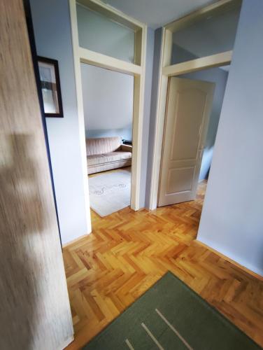 a hallway with an open door and a room with wood floors at Apartman Aleksandra in Smederevo