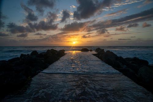 un coucher de soleil sur l'océan avec une jetée avec des rochers dans l'établissement LE STUDIO D'ANTXETA Vue Océan, à 2 pas de Guethary, à Saint-Jean-de-Luz