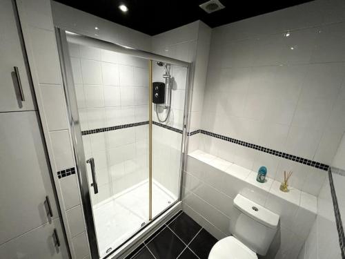 uma casa de banho branca com um chuveiro e um WC. em Winter Gardens North Pier 2 Bed em Blackpool