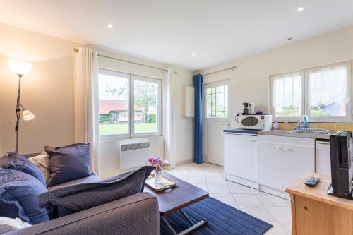 un salon avec un canapé et une cuisine dans l'établissement Le Cottage Normand, à Annebault