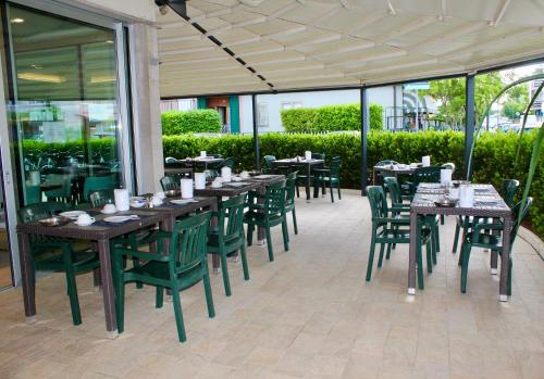 a restaurant with wooden tables and green chairs at Hotel Cristina in Grado