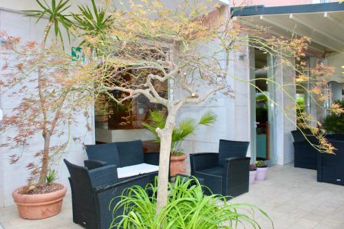 a patio with chairs and a tree in front of a building at Hotel Cristina in Grado
