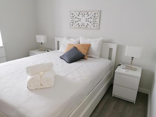 ein Schlafzimmer mit einem weißen Bett und Handtüchern darauf in der Unterkunft Miragaia Star Apartments in Angra do Heroísmo