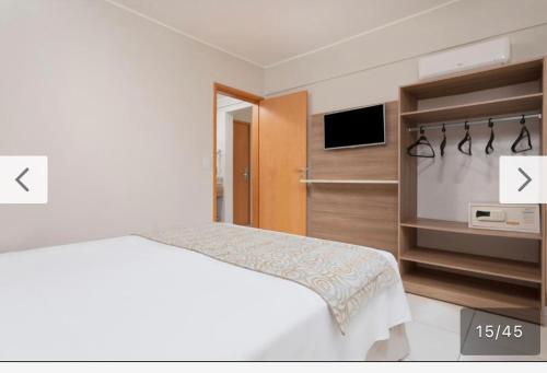a white bedroom with a bed and a television at Apartamento em Resort Olímpia in Olímpia