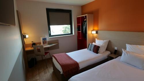 オベルネにあるOneloft Hotelのベッド2台とデスクが備わるホテルルームです。
