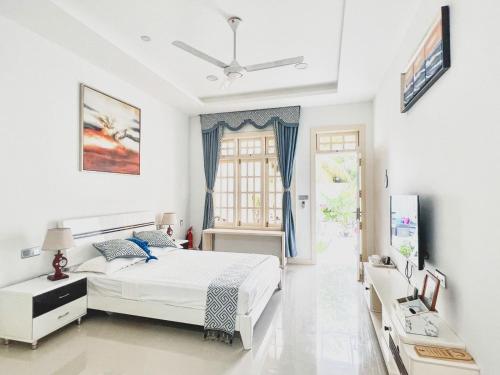 a white bedroom with a bed and a window at Fiyala Homestay in Feydhoo