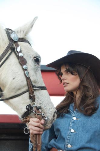 a woman wearing a hat standing next to a white horse at 3 Hills Boutique - The Ranch Experience in Trílofos