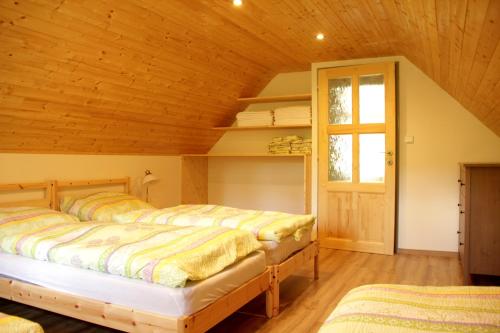 two beds in a room with a wooden ceiling at Chalupa Nové Losiny in Nové Losiny