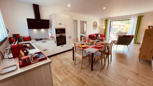 a kitchen and living room with a table and chairs at Villa moderne avec spa à Montalivet in Vensac