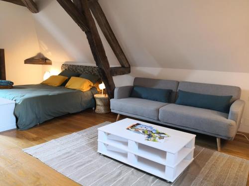 ein Wohnzimmer mit einem Sofa und einem Bett in der Unterkunft La ferme de la Terve in Bruailles