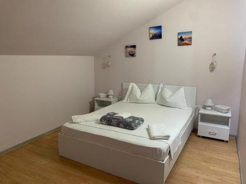 a bedroom with a white bed with a black purse on it at R i A N A 2 in Eforie Sud