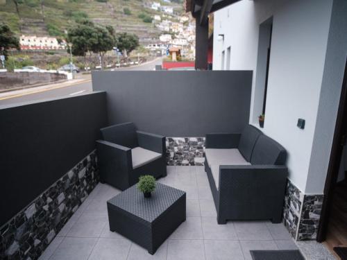 a balcony with two chairs and a table and a window at Village Center Two Bedroom Apartment in Porto Moniz