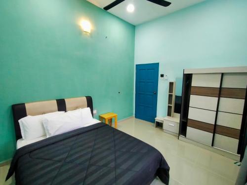 a bedroom with a bed and a blue wall at anjung ara suites and roomstays in Kuala Terengganu
