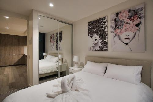 Schlafzimmer mit einem weißen Bett und einem Spiegel in der Unterkunft Queen Bed Luxury Parisian Paradise with Amazing City Views, Spa, Gym, Steam & Sauna Rooms in Adelaide