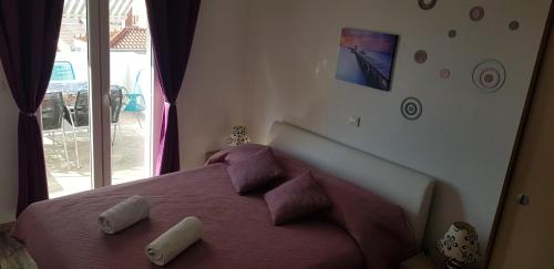 a bedroom with a bed with purple sheets and a window at Villa Paladina in Hvar
