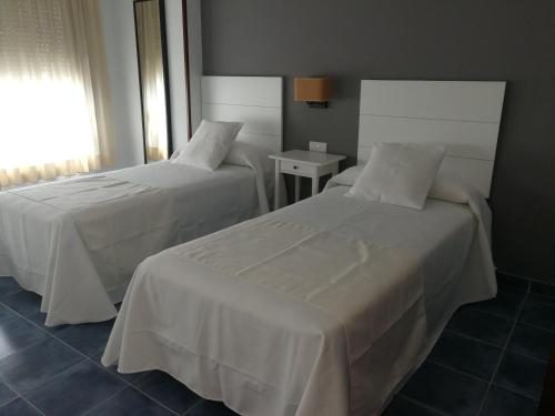 a hotel room with two beds with white sheets at PENSION CASA JULIO ** in Culleredo