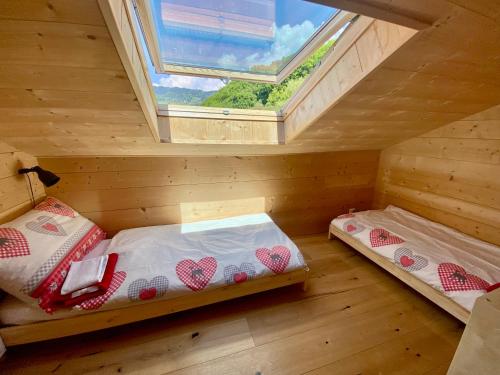 two beds in a wooden room with a window at Chalet Rouge Coeur in Fenalet Sur Bex
