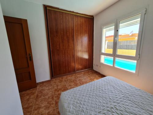 a bedroom with a bed and a window at Beach Villas 16 con piscina privada in Caleta De Fuste