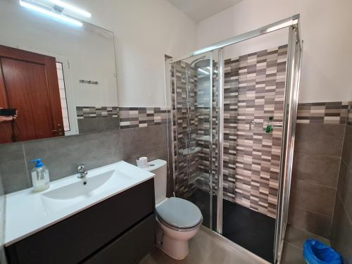 a bathroom with a toilet and a sink and a shower at Beach Villas 16 con piscina privada in Caleta De Fuste