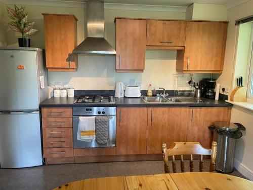 una cocina con armarios de madera y un aparato de acero inoxidable en global relocation 2 Bed Apt Near Hatfield Station Free Parking, en Hatfield
