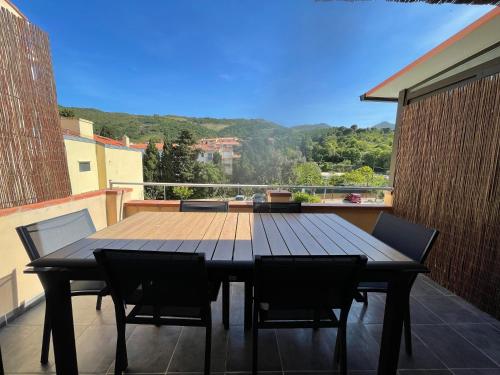a wooden table and chairs on a balcony at Ibanova Appartements in Collioure