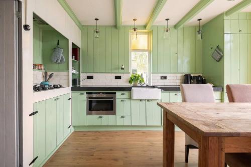 a kitchen with green cabinets and a wooden table at Private Characteristic farmhouse near the lake in Andijk