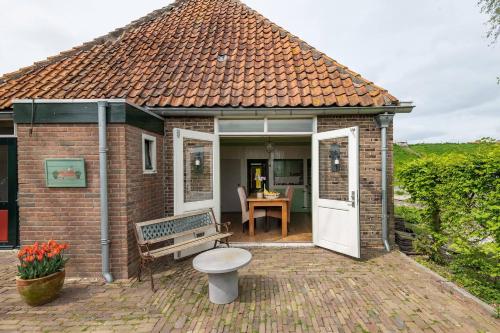 a small brick house with a bench and a table at Private Characteristic farmhouse near the lake in Andijk