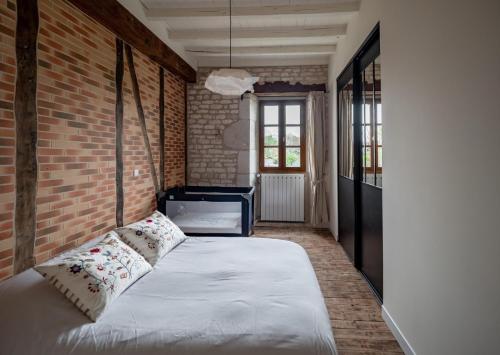 un lit dans une chambre avec un mur de briques dans l'établissement Maison de vacances L'Hermione, à Villeneuve-sur-Vère