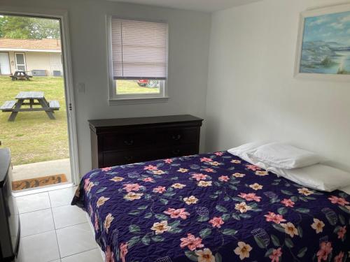 a bedroom with a bed with a floral blanket and a window at Riviera Motor Lodge in Myrtle Beach