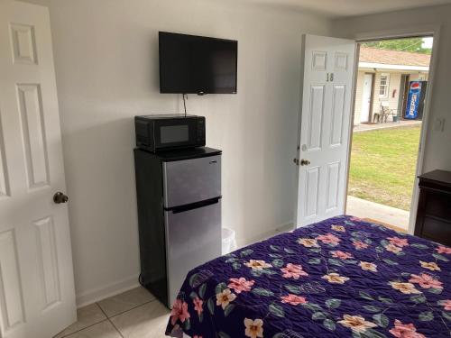 1 dormitorio con 1 cama con microondas y TV en Riviera Motor Lodge, en Myrtle Beach