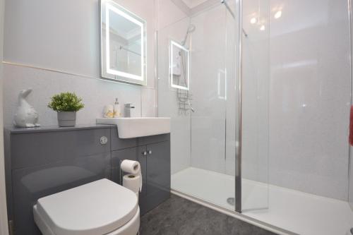 a bathroom with a shower and a toilet and a sink at Unique restored Old Post Office in Kinlochleven