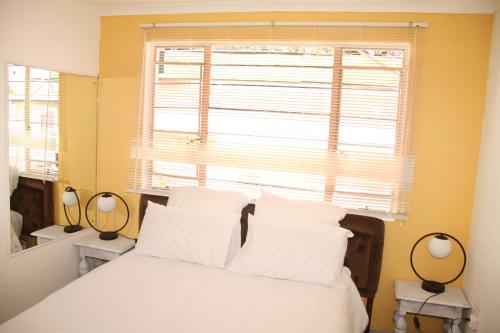ein Schlafzimmer mit einem weißen Bett und einem Fenster in der Unterkunft Lovely 1-bedroom flat in Germiston in Germiston