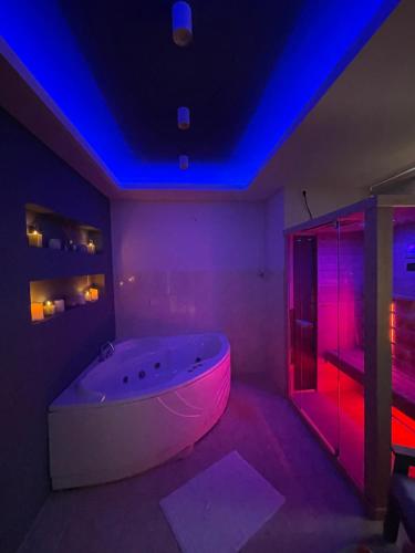 una vasca bianca in una stanza con luci viola di Apartman Spa Bačka a Bačka Palanka