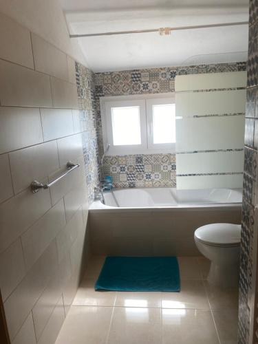 a bathroom with a tub and a toilet and a window at Quinta de Areias in Crespos