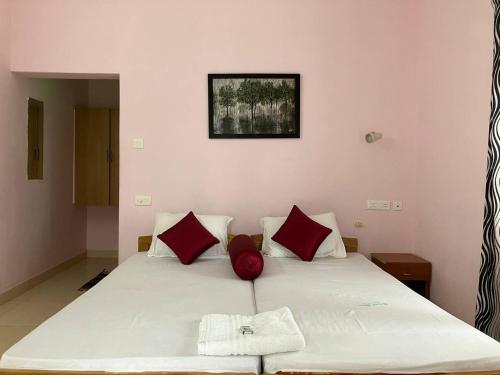 um quarto com uma cama branca e almofadas vermelhas em Coral Cove Beach Resort em Varkala