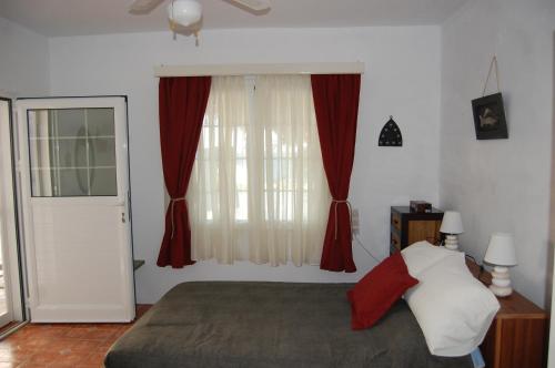 a bedroom with a bed and a window with red curtains at COSY STUDIO IN ALLOPRONOIA SIKINOS in Alopronia