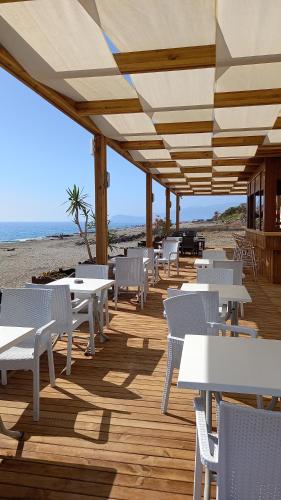 een houten terras met witte tafels en stoelen op het strand bij Galaxy Beach Hotel Alanya in Mahmutlar