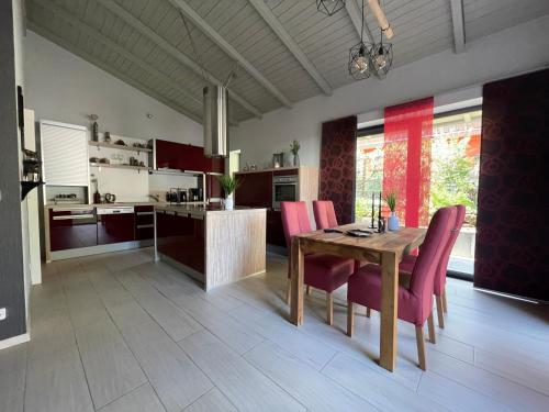 eine Küche mit einem Holztisch und rosa Stühlen in der Unterkunft Ferienhaus Nicole II, Barrierefrei, mit HIRO Lift in Quedlinburg