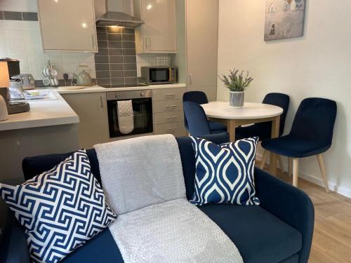 a living room with a blue couch and a kitchen at Seaside Escape in St Ives